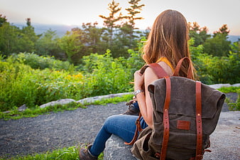 Woman with Backpack Sitting on Rock Overlooking Forest