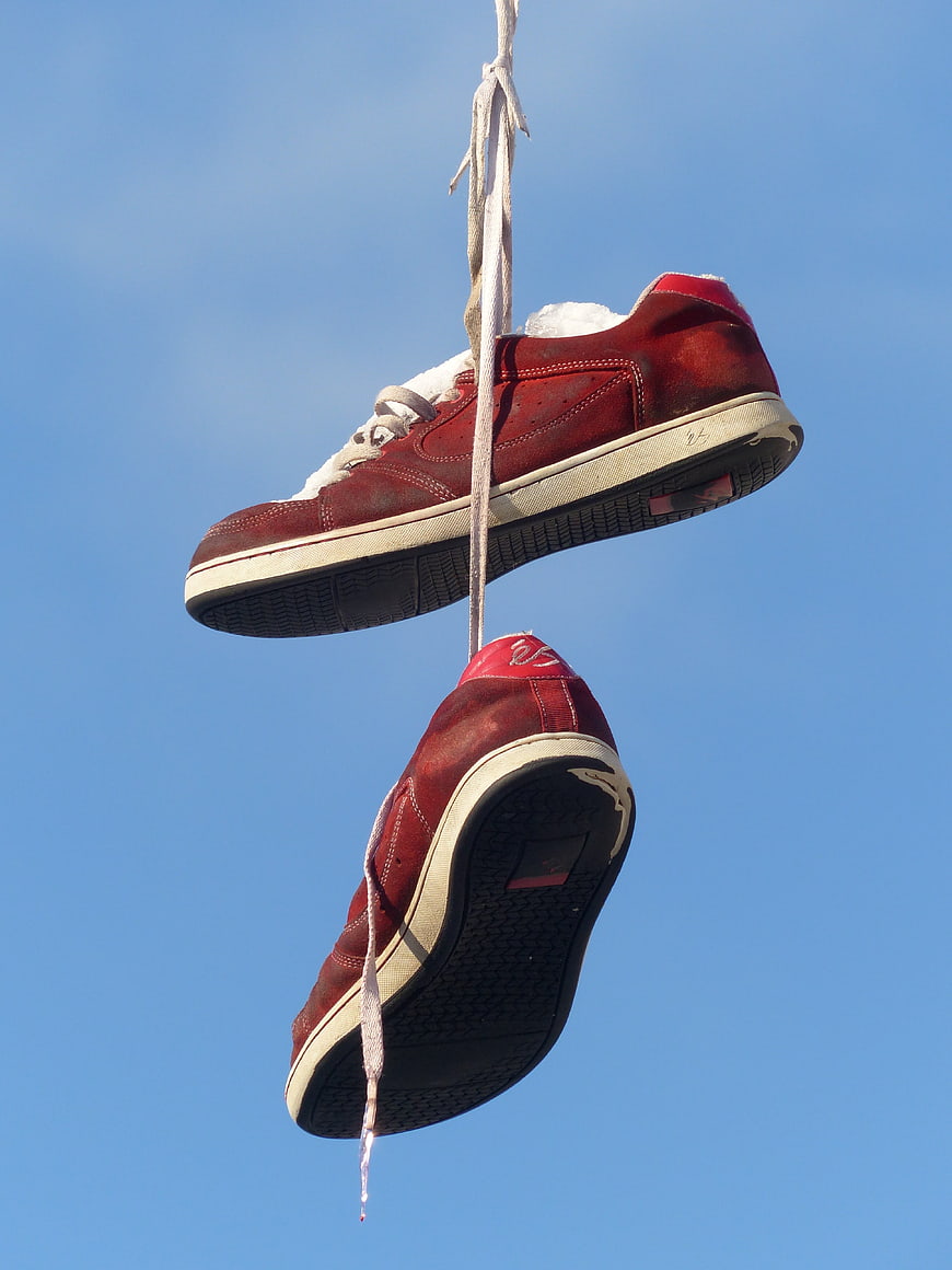 Red Sneakers Hanging From Rope Against Blue Sky