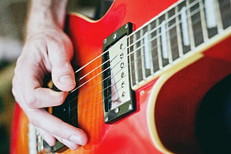 Close-up of hand playing red electric guitar
