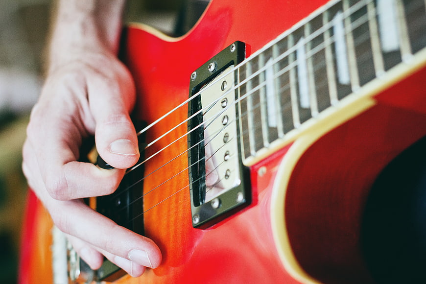 Close-up of hand playing red electric guitar