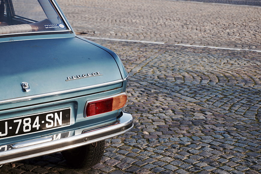 Rear View of Vintage Blue Peugeot on Cobblestone Street