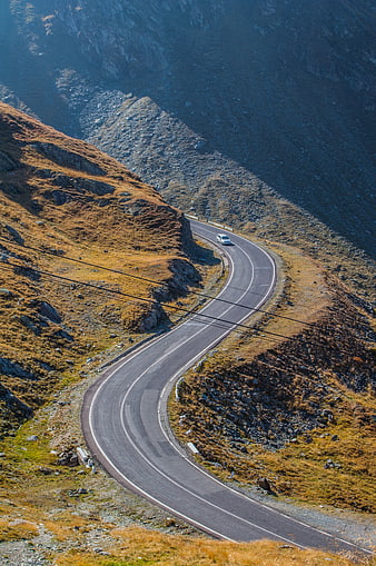 Winding mountain road with car in autumn landscape