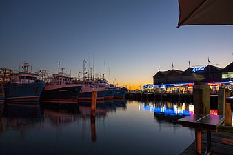 Fishing boats docked at harbor during twilight with neon lights