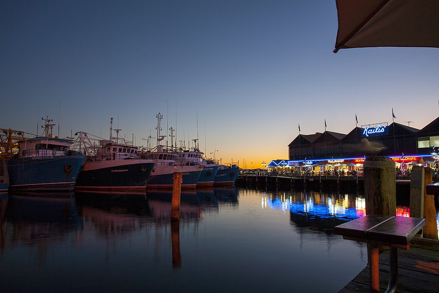 Fishing boats docked at harbor during twilight with neon lights