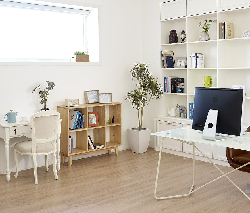 Bright modern home office with white furniture and wooden shelves