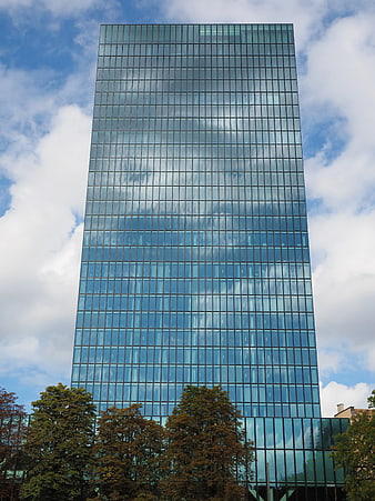 Modern glass skyscraper reflecting clouds and blue sky