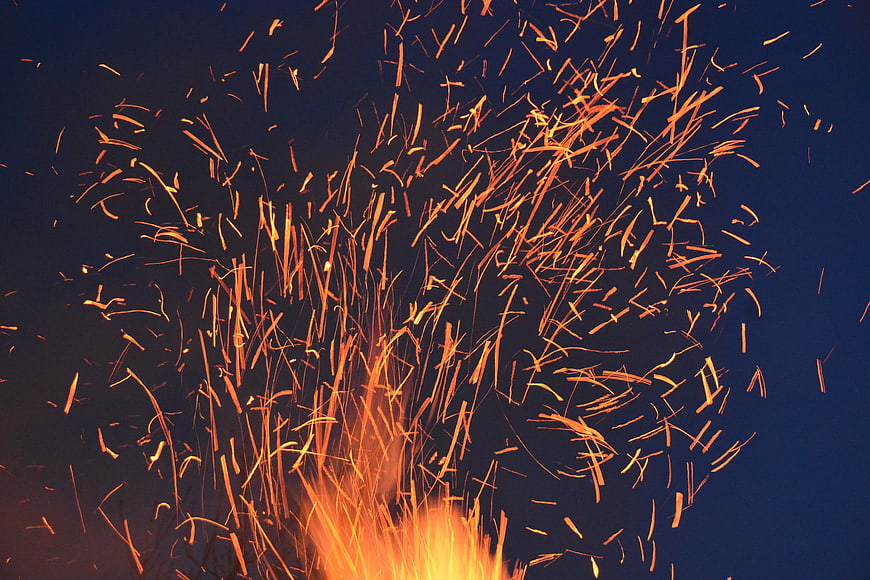 Dynamic burst of orange sparks against dark blue background