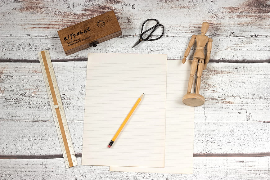 Top view of school supplies on white wooden background