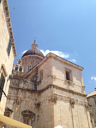 Low angle view of historic stone church with dome against blue sky