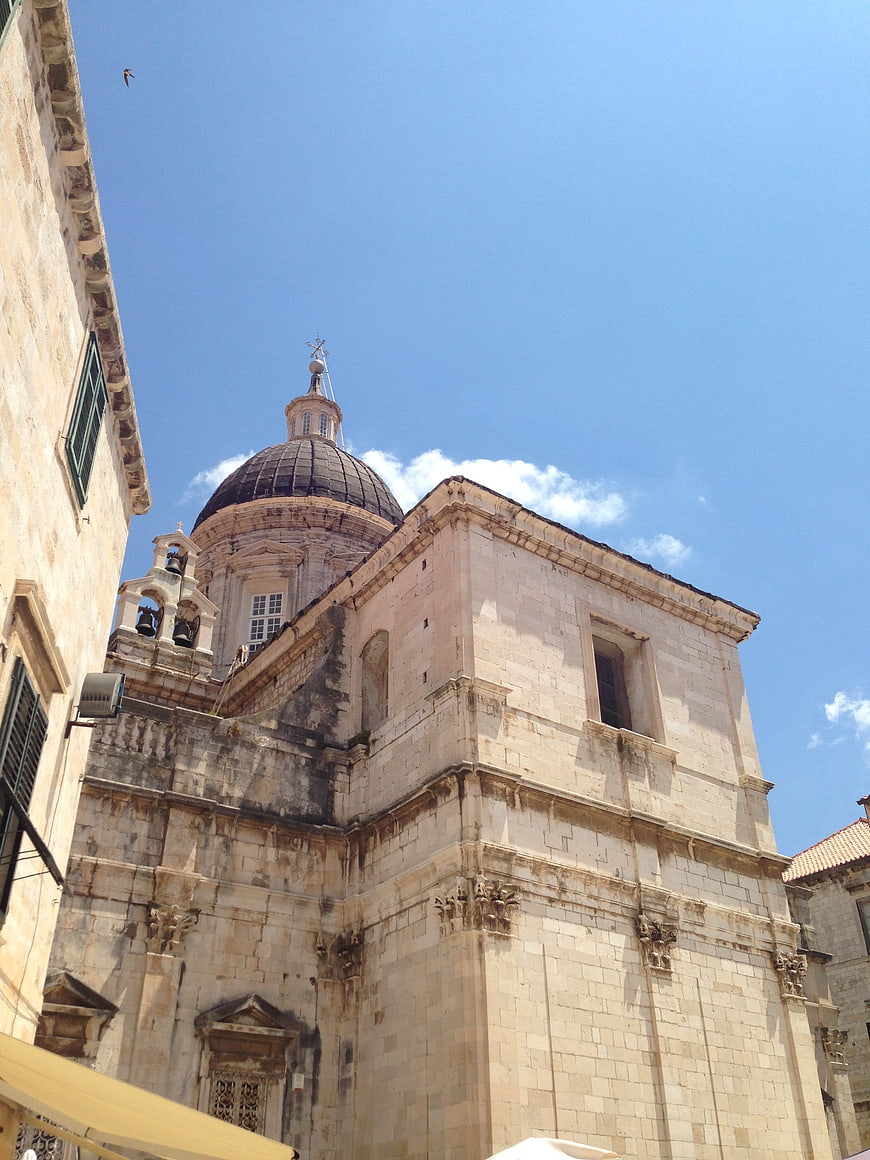 Low angle view of historic stone church with dome against blue sky