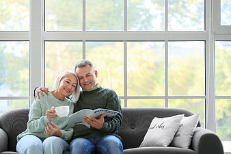 Happy Senior Couple Reading Magazine on Sofa