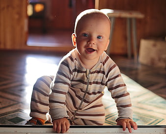 Happy baby crawling on wooden floor with sunlight