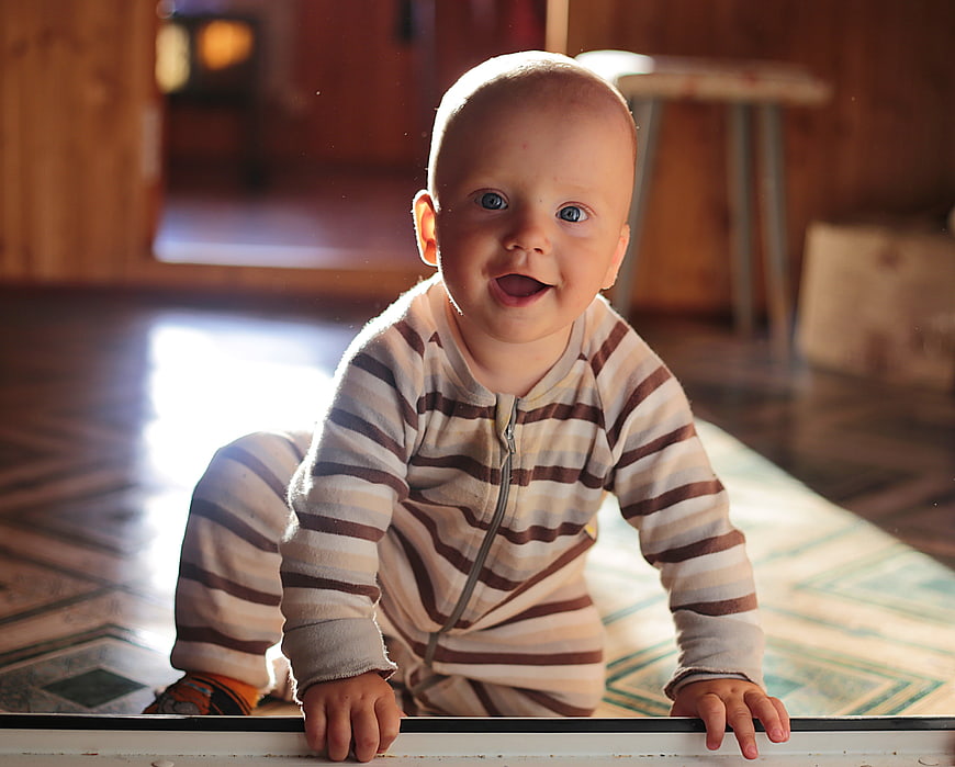 Happy baby crawling on wooden floor with sunlight