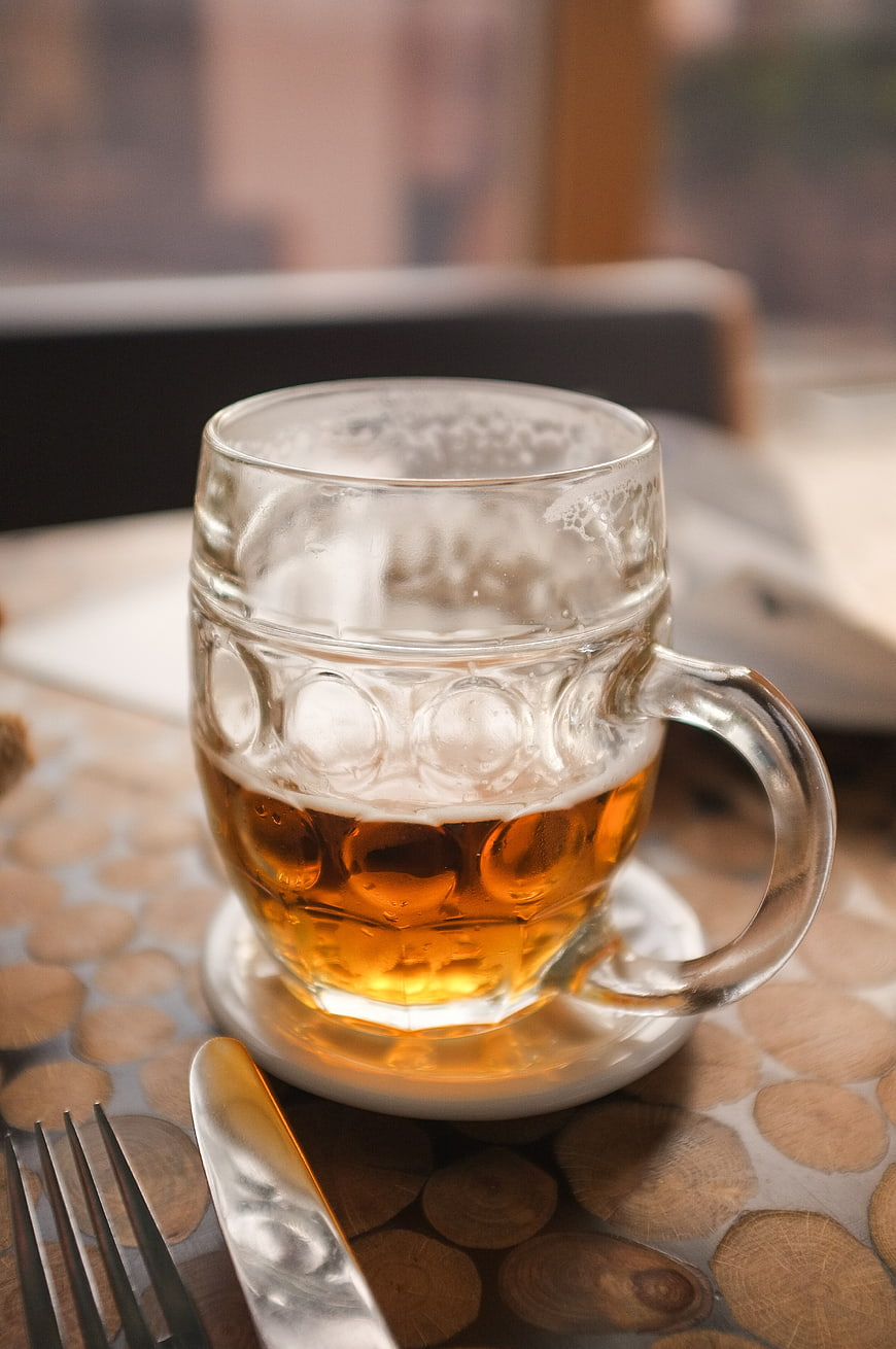 Half-full glass of beer on wooden table