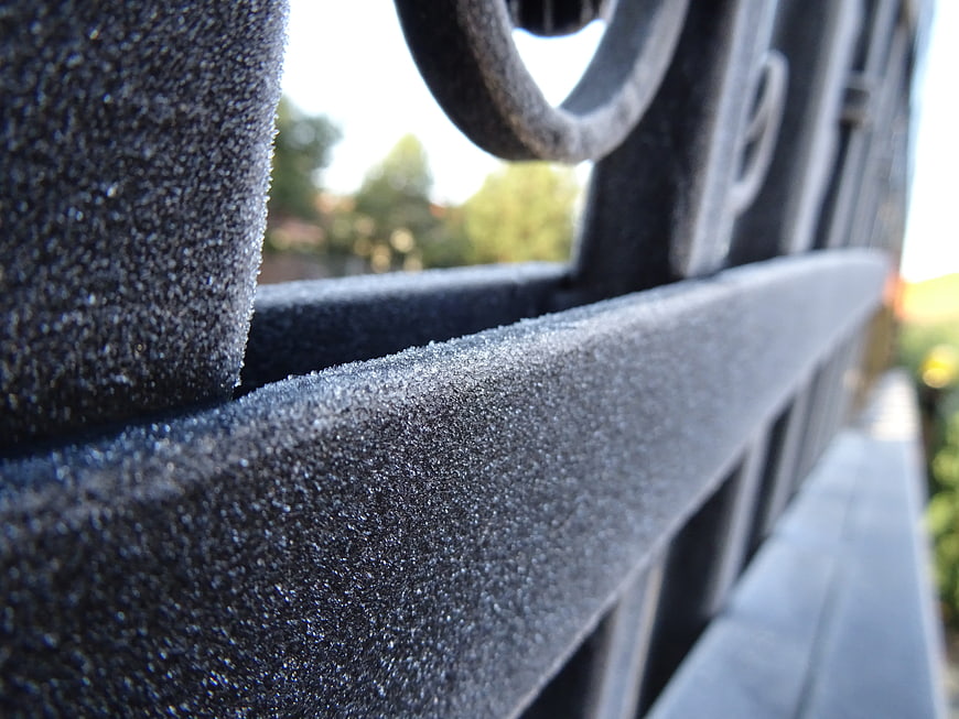 Close-up of frost crystals on a black metal railing