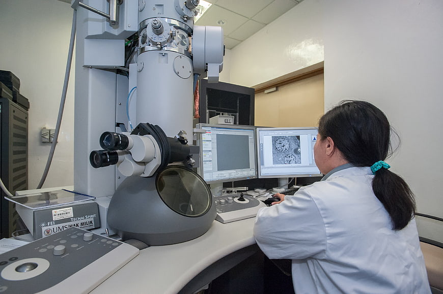 Scientist operating a transmission electron microscope in a laboratory
