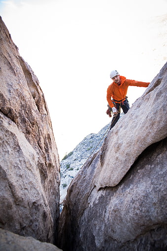 Man rock climbing in narrow canyon crevice