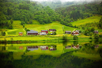 Scenic Norwegian village with houses reflecting in calm lake water