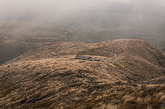 Lone cabin on misty mountain ridge with winding path