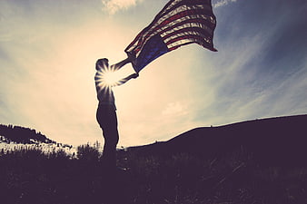 Man Waving American Flag Silhouette Against Sunset Sky