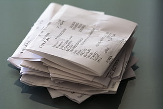 Stack of paper receipts on a green table surface