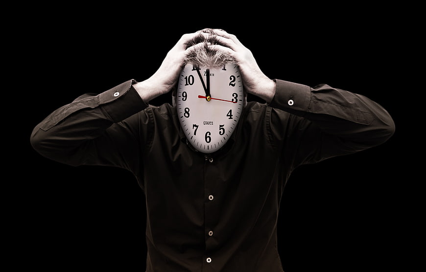 Man with clock face holding head in stress
