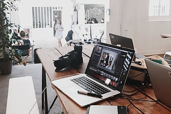 Laptop and Camera on Wooden Desk in Busy Studio
