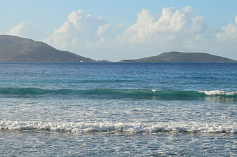 Serene ocean waves rolling toward shore with distant islands