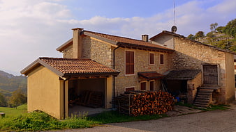 Rustic stone farmhouse with woodpile in Italian countryside