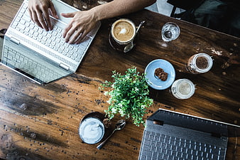 Top view of hands typing on laptop with coffee and workspace