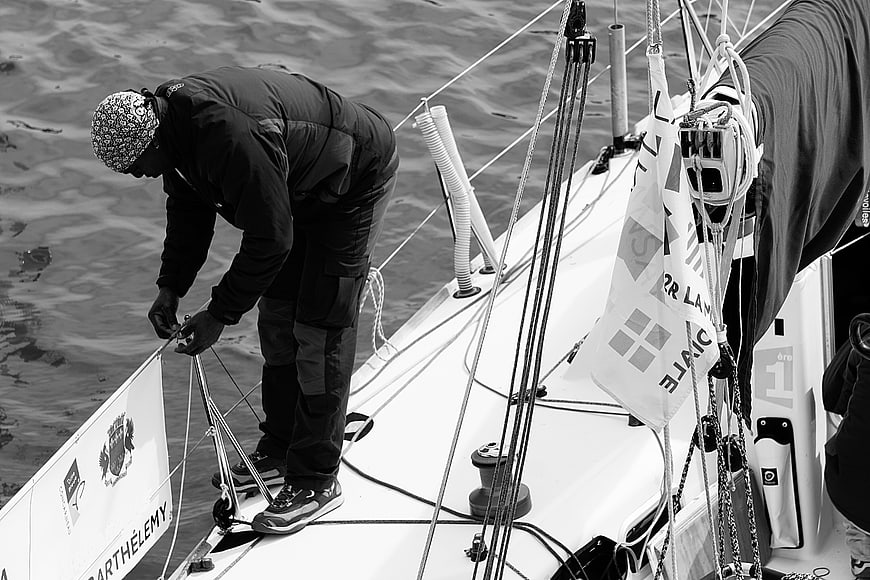Sailor adjusting ropes on a yacht deck in black and white