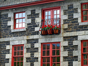 Red window frames on stone building facade with flowers