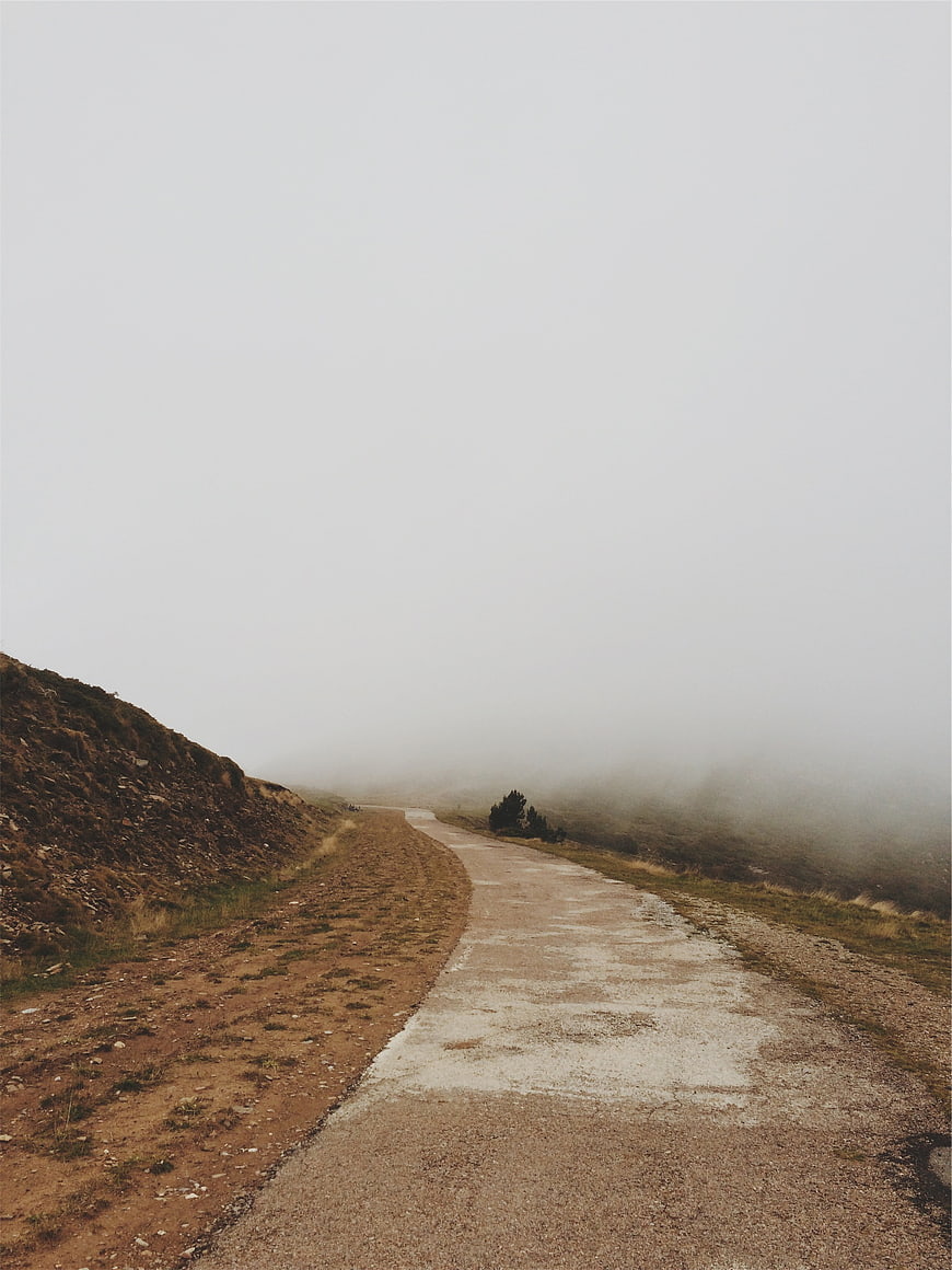 Foggy gravel road winding through misty mountain landscape