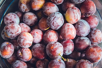 Close-up of fresh purple plums in a glass bowl