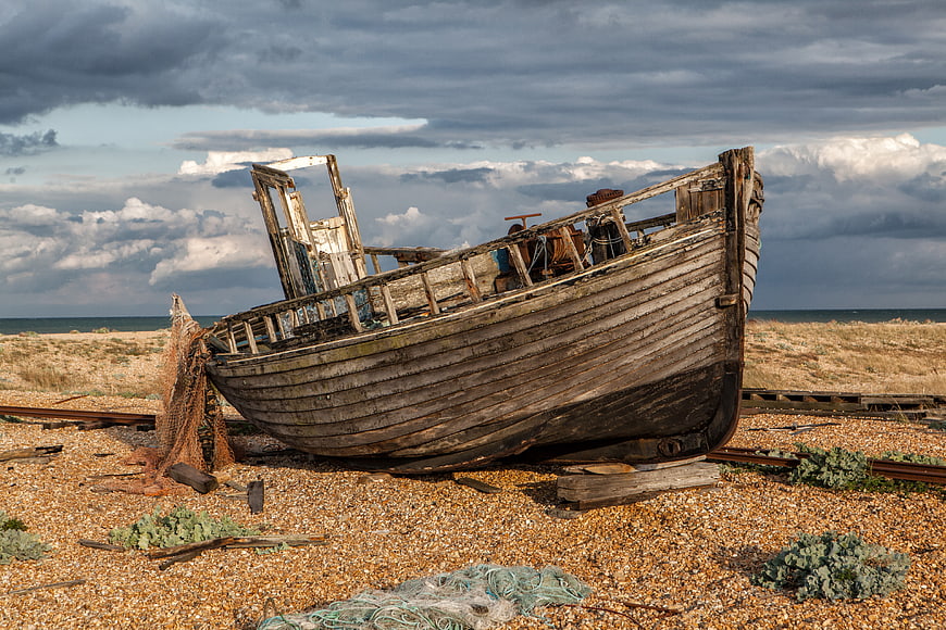 Abandoned wooden fishing boat on pebble beach