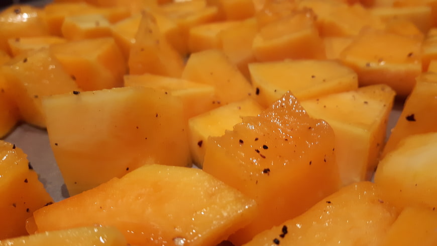 Seasoned raw pumpkin cubes ready for roasting