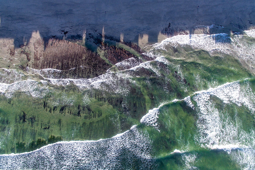 Aerial View of Green Ocean Waves Crashing on Sandy Beach