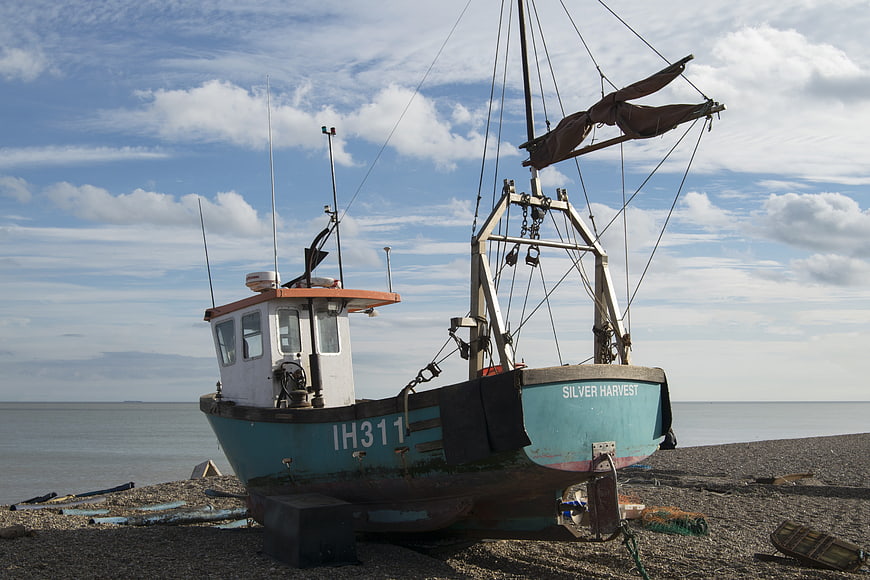 Weathered fishing boat Silver Harvest on pebble beach