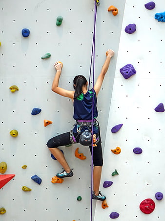 Woman rock climbing on indoor wall with colorful holds