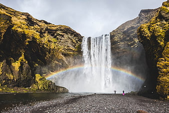 Skogafoss Waterfall in Iceland with Rainbow and Hikers