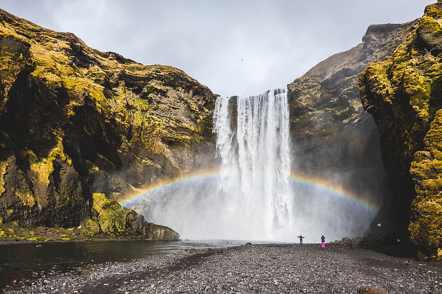 Skogafoss Waterfall in Iceland with Rainbow and Hikers