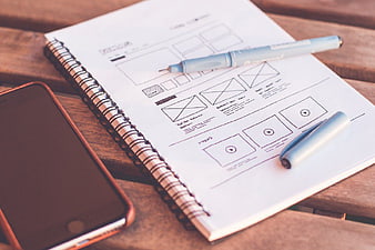 Hand-drawn UX wireframe sketch on notebook with smartphone