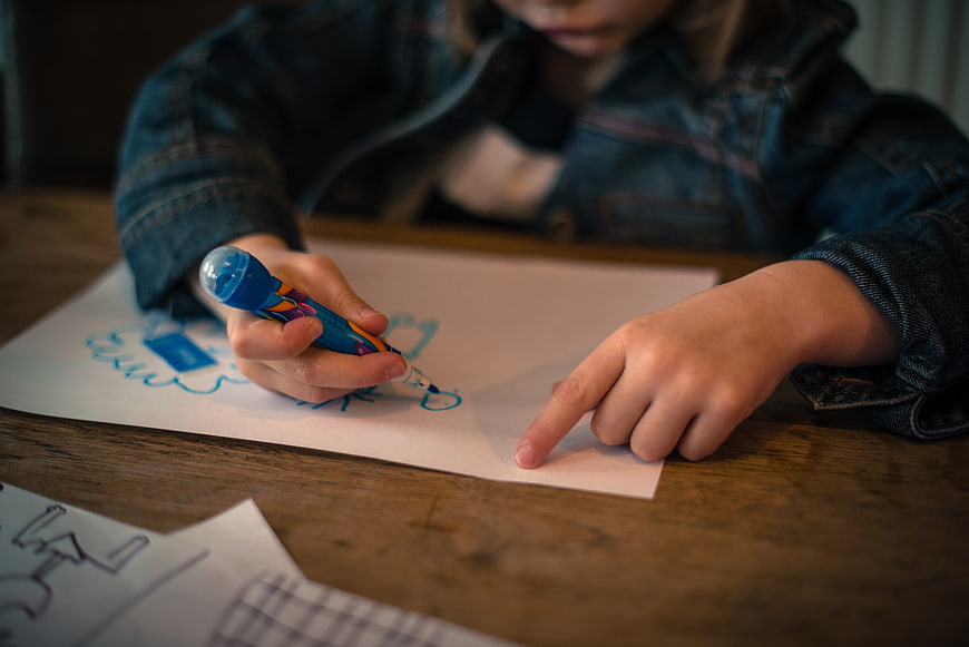 Child Drawing with Blue Marker on Paper