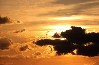 Dramatic golden sunset sky with dark clouds and bright sun rays