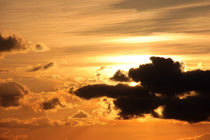 Dramatic golden sunset sky with dark clouds and bright sun rays