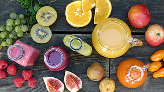 Flat lay of fresh fruit juices, smoothies, and whole fruits on dark wood