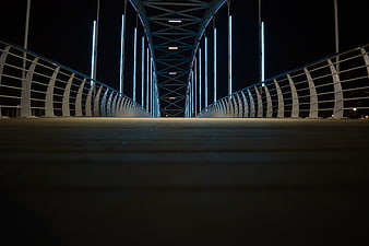 Low angle night view of modern steel bridge with blue neon lights