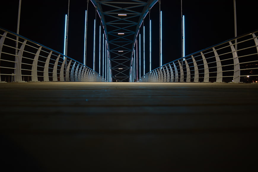 Low angle night view of modern steel bridge with blue neon lights