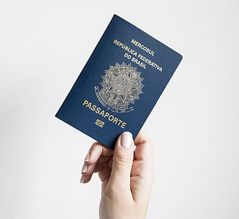 Hand holding Brazilian passport against white background