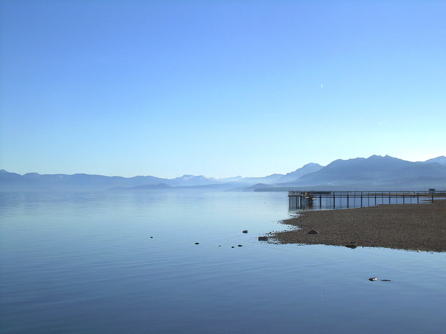 Serene Lake Landscape with Wooden Pier and Distant Mountains